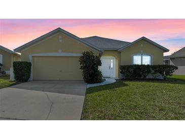 Charming home featuring manicured lawn, two-car garage, and welcoming front entrance at 647 Ella Mae Dr, Davenport, FL 33897