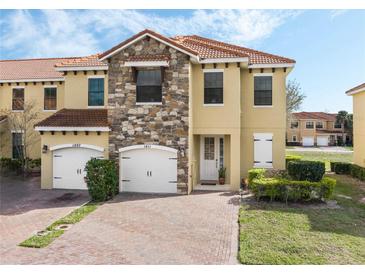 Charming townhouse showcasing a stone facade, red tile roof, and a brick driveway at 1411 Pacific Rd, Poinciana, FL 34759