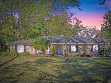 Charming single-story home featuring a well-manicured lawn, mature trees, and inviting blue front door at 33639 Wesley Rd, Eustis, FL 32736