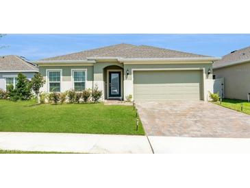 Inviting single-story home with a manicured lawn, brick driveway, and a two-car garage at 592 Jupiter Beach Rd, Groveland, FL 34736