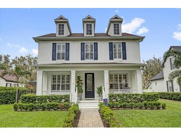 Stunning two-story home with a welcoming front porch, blue shutters, and professionally landscaped yard at 11402 Camden Loop Way, Windermere, FL 34786