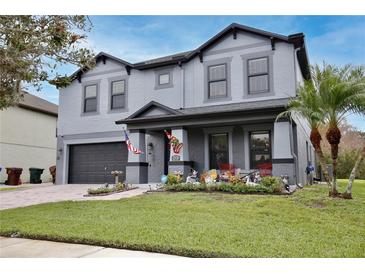 Charming two-story home featuring gray paint, well-manicured lawn, and an attached two-car garage at 2926 Boating Blvd, Kissimmee, FL 34746