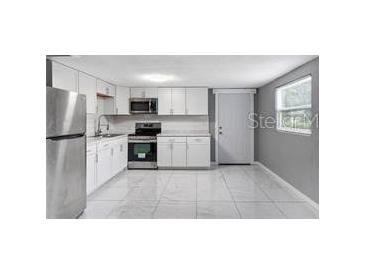 Bright kitchen featuring white cabinets, stainless steel appliances, and tile flooring at 630 N Nashua Ave, Fort Meade, FL 33841