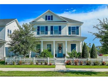 Charming two-story home featuring blue shutters and a well-manicured lawn with a white picket fence at 1024 Prosperity Dr, Winter Garden, FL 34787