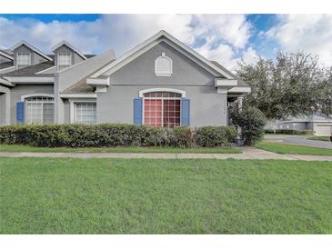 Charming home exterior featuring gray stucco, blue shutters, and well-maintained landscaping in a residential neighborhood at 13046 Island Breeze Ct, Orlando, FL 32824