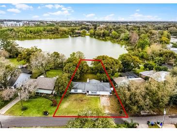 Aerial view showcases the property's location on a lake with mature trees and a spacious yard at 1890 Twin Lake Dr, Gotha, FL 34734