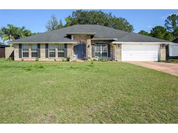 Charming single-story brick home with a well-manicured lawn, blue front door, and attached garage at 2454 Whitehorse St, Deltona, FL 32738