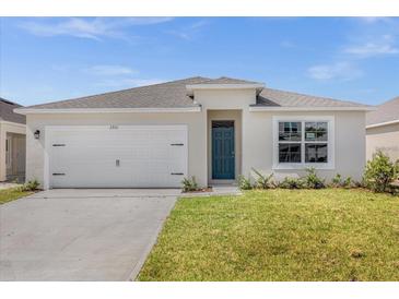 Charming single-story home featuring a neatly manicured lawn, attached two-car garage, and blue front door at 2921 Sunridge Loop, St Cloud, FL 34771