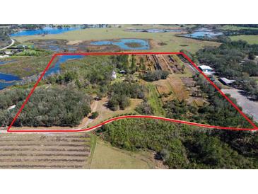 Expansive property featuring diverse landscaping, waterways and agricultural fields with a red boundary line at 8122 Pine Island Rd, Clermont, FL 34711
