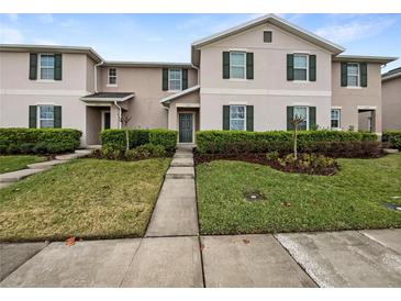 Inviting townhouse exterior boasts manicured landscaping, a concrete walkway and beautiful green shutters at 1613 Reflection Cv, St Cloud, FL 34771