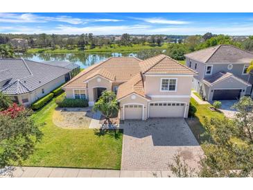 An inviting two-story home with a tile roof and a three-car garage is situated with views of a tranquil lake at 1950 Windward Oaks Ct, Kissimmee, FL 34746