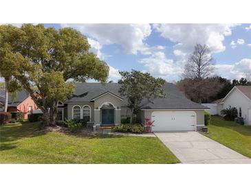 Charming home featuring lush landscaping, arched windows, and a well-maintained lawn and a two-car garage at 2121 Knollview Ct, Oviedo, FL 32765