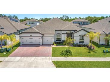 Charming one-story home featuring a three-car garage, brick driveway, lush green lawn and manicured landscaping at 3351 Pine Timber Pt, Oviedo, FL 32765