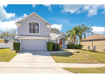 Charming two-story home featuring a well-manicured lawn and an attached two-car garage at 511 Coventry Rd, Davenport, FL 33897