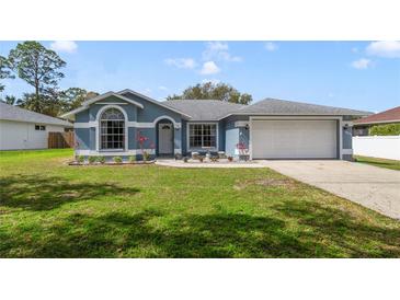 Charming single-story home with blue siding, well-manicured lawn, and a two-car garage at 607 S Glencoe Rd, New Smyrna Beach, FL 32168