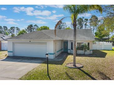 Charming single-story home featuring a well-manicured lawn, two-car garage, and a lush palm tree in the front yard at 100 Diamond Ridge Blvd, Auburndale, FL 33823