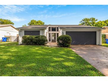 Charming home featuring a well-manicured lawn, gray trim, a two car garage, and a modern entrance at 1244 Spinnaker Dr, Lakeland, FL 33805