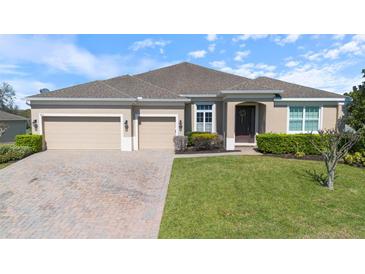 Charming single-story home boasts a well-manicured lawn, paver driveway and three-car garage at 1407 Leitrim Loop, Apopka, FL 32703