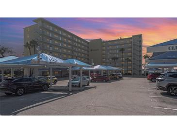 Exterior view of Harbor View building featuring covered parking and vibrant sunset in Indian Rocks Beach, Florida at 145 N Halifax Ave # 601, Daytona Beach, FL 32118