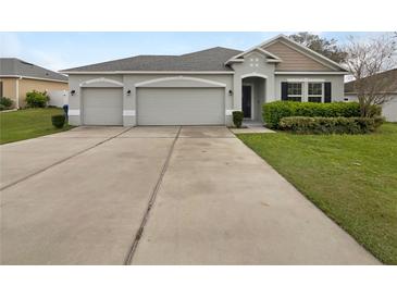 Charming home featuring a wide driveway, manicured lawn, and a welcoming entrance at 15120 Zenith Ave, Mascotte, FL 34753