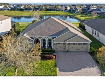 Beautiful home exterior with a three car garage, well manicured lawn, and a serene lake in the background at 15993 Johns Lake Overlook Dr, Winter Garden, FL 34787