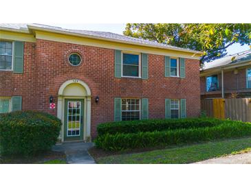 Charming brick condo featuring a front door beneath an archway, complemented by green shutters and lush landscaping at 524 Georgetown Dr # A, Casselberry, FL 32707