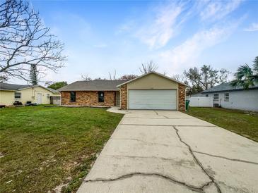 Charming single-story brick home with a well-maintained lawn and a two-car garage at 832 Yellowbird Ave, Deltona, FL 32725