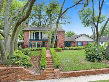 Charming two-story brick home featuring a lush front yard and inviting balcony at 1804 Wind Willow Rd, Belle Isle, FL 32809