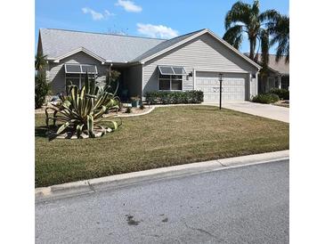 Well-maintained home featuring mature landscaping, a two-car garage, and a neatly manicured lawn at 419 Aldama Ave, Lady Lake, FL 32159