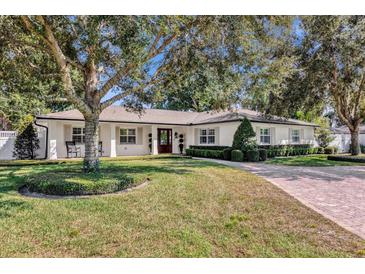 Charming single-story home with manicured lawn, brick driveway, mature trees, and white shutters at 5205 Saint Regis Pl, Belle Isle, FL 32812