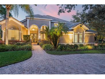 Stately home featuring a beautifully paved driveway, lush landscaping, and an inviting gated entrance at twilight at 1613 Glenwick Dr, Windermere, FL 34786