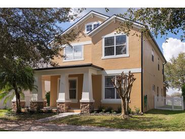 Charming two-story home featuring a well-manicured lawn and inviting front porch with stone and pillar accents at 2934 Wild Tamarind Blvd, Orlando, FL 32828