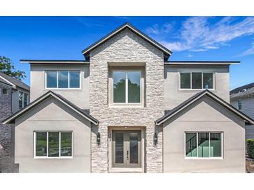 Elegant two-story home featuring a stone facade and modern windows, set against a vibrant blue sky at 3206 Harrison Ave, Orlando, FL 32804