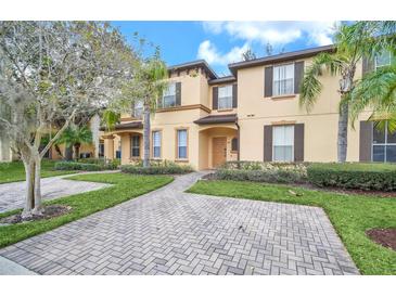 Charming tan two-story townhome with well-maintained landscaping and a brick-paved walkway at 438 Miramar Ave, Davenport, FL 33897