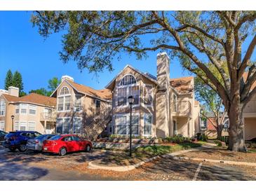 Inviting condo exterior featuring a chimney, tan siding, and mature shade trees at 675 Youngstown Pkwy # 258, Altamonte Springs, FL 32714