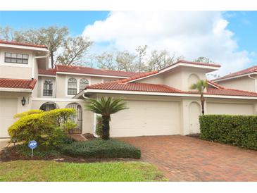 Charming townhome featuring a well-maintained exterior, red tile roof, and a paver driveway leading to a two-car garage at 7536 Fenwick Cove Ln, Orlando, FL 32819