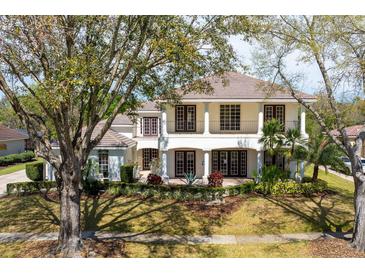 Beautiful two-story home featuring manicured landscaping, a tile roof, and a welcoming columned front porch at 8661 Crestgate Cir, Orlando, FL 32819