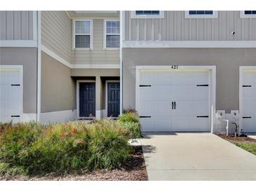 Townhome exterior with painted facade, white garage door, black hardware, and landscaped front yard at 421 Sedgewick Dr, Davenport, FL 33837