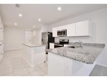 Modern kitchen features granite counters, stainless steel appliances, a center island, and bright lighting at 421 Sedgewick Dr, Davenport, FL 33837