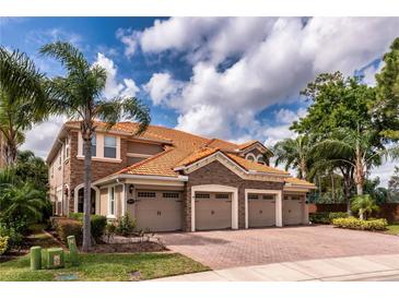 Beautiful home featuring a clay tile roof, stone accents, and a spacious three-car garage at 8950 Della Scala Cir, Orlando, FL 32836