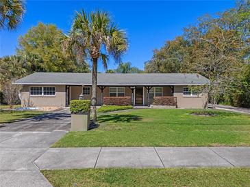 Charming single-story home featuring a well-manicured lawn, mature trees, and a welcoming front porch at 10031 Union Park Dr, Orlando, FL 32817