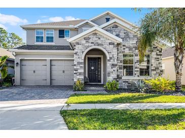 Beautiful two-story home with stone facade, three-car garage, and well-maintained landscaping at 10699 Petrillo Way, Winter Garden, FL 34787