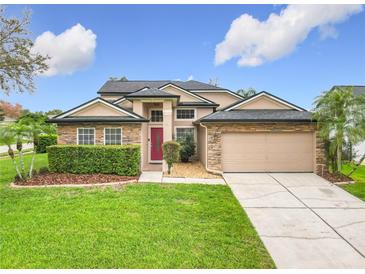 Charming home featuring stone accents, a well-manicured lawn, and a welcoming red front door at 1609 River Birch Ave, Oviedo, FL 32765