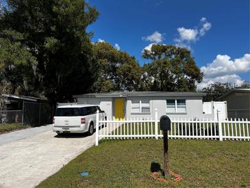 Charming single-story home with a bright yellow door, white picket fence and well-maintained front yard at 4407 Lake Lawne Ave, Orlando, FL 32808