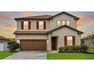 Two-story home with a two-car garage, neutral paint, red shutters, and well-maintained landscaping at 5607 Western Sky Pl, St Cloud, FL 34771