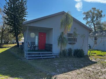 Charming home featuring light siding, red front door, and quaint covered porch at 586 N 8Th St, Eagle Lake, FL 33839