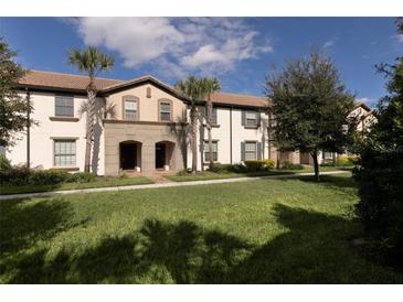 Inviting townhouse with a well-maintained lawn, palm trees, and covered entrances at 8912 Adriatico Ln, Kissimmee, FL 34747