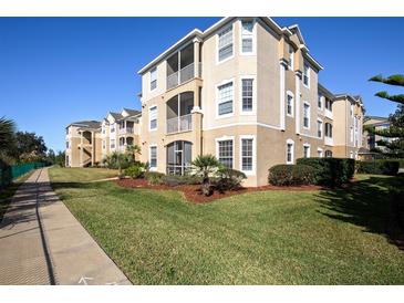 Well-maintained exterior of a multi-story building with lush lawn, mature trees, and manicured landscaping at 2304 Silver Palm Dr # 103, Kissimmee, FL 34747