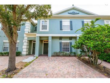 Charming two-story townhome with brick driveway and lush landscaping, offering curb appeal and a welcoming entrance at 2412 Caravelle Cir, Kissimmee, FL 34746