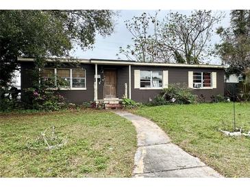 Modest single-story home with a brown exterior and a walkway leading to the front entrance at 4322 Lancashire Ln, Orlando, FL 32812
